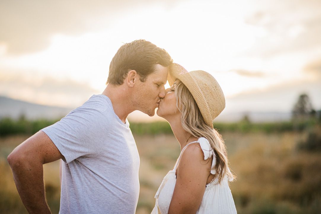 A couple shares a tender moment while dancing in a golden field at sunset.