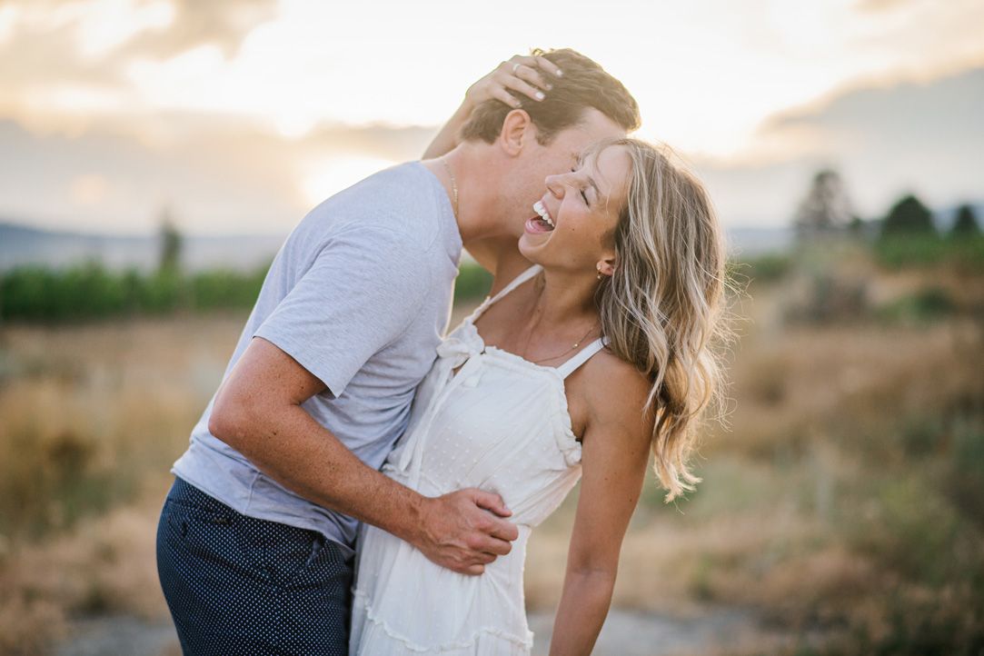 Intimate moment between couple during golden hour photoshoot in rustic outdoor setting.
