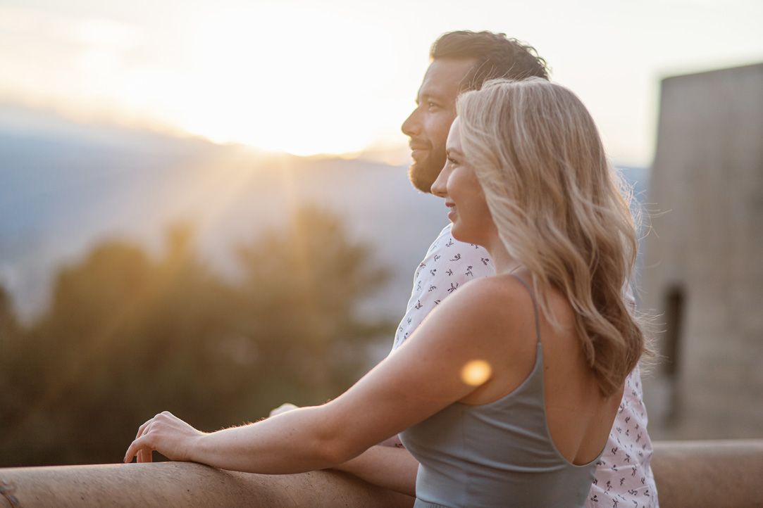 Couple enjoying sunset together on outdoor patio with string lights.