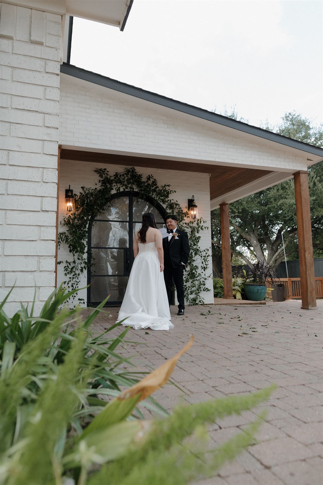 Modern white chapel entrance decorated with greenery arch and lanterns for a wedding ceremony.