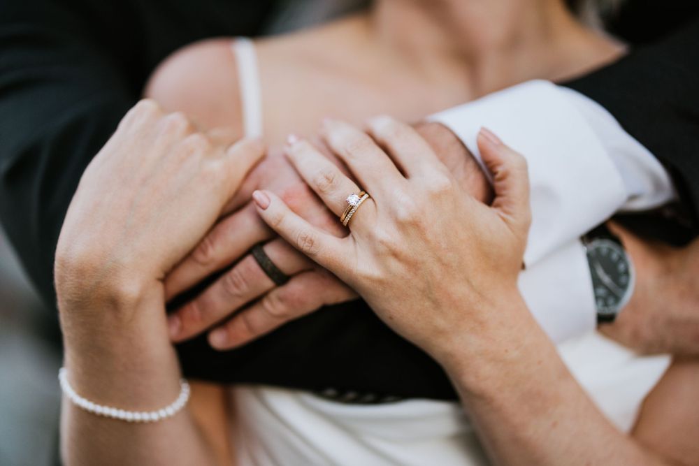 Close-up shot of hands with wedding rings showing an intimate moment.