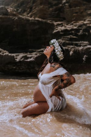 Artistic beach portrait showing person in flowing white fabric reclining on sandy shore.