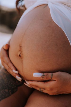 Close-up of pregnant belly with delicate tattoo details.