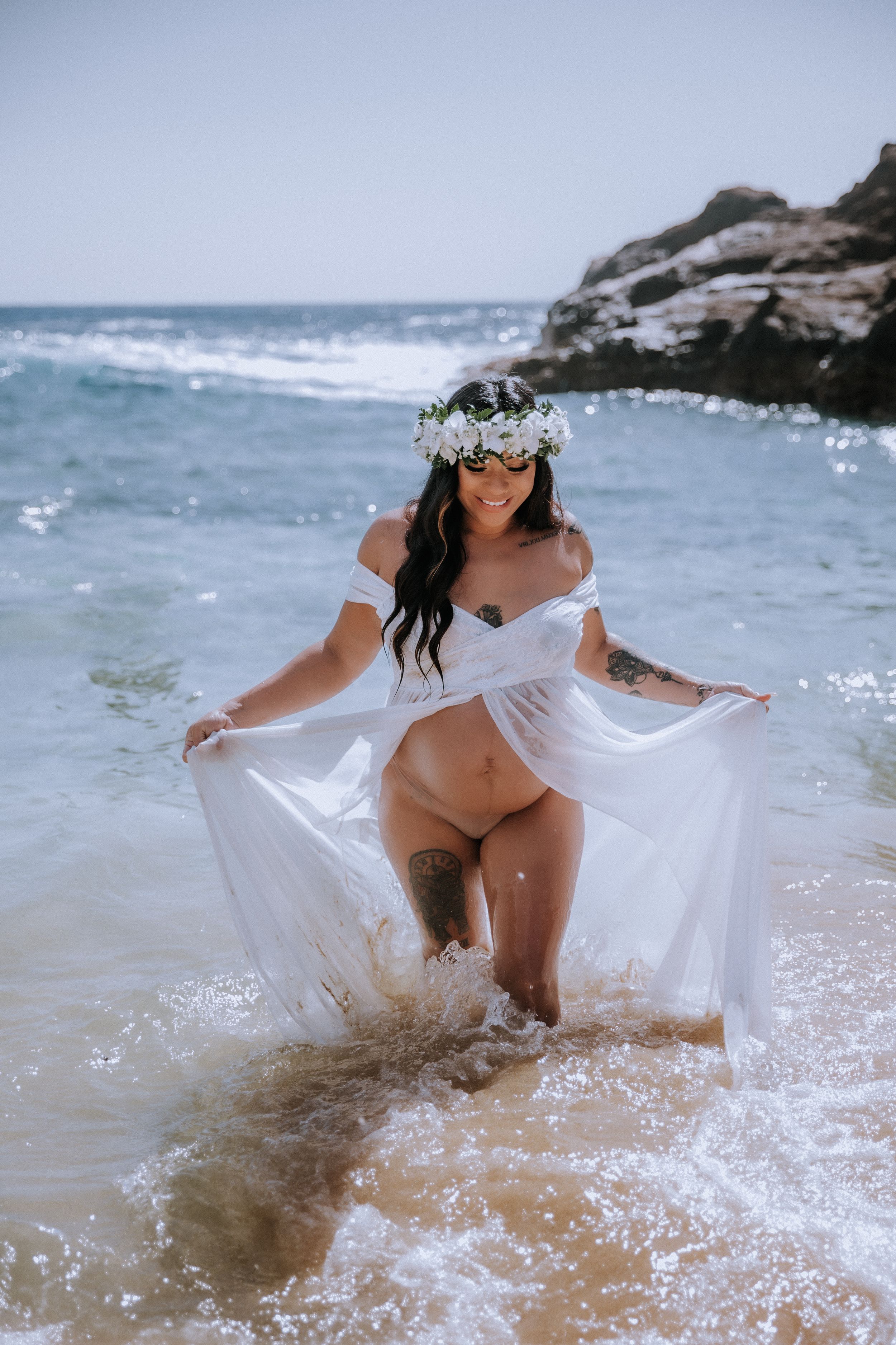 Ethereal beach photography with person in white dress playing in ocean waves.