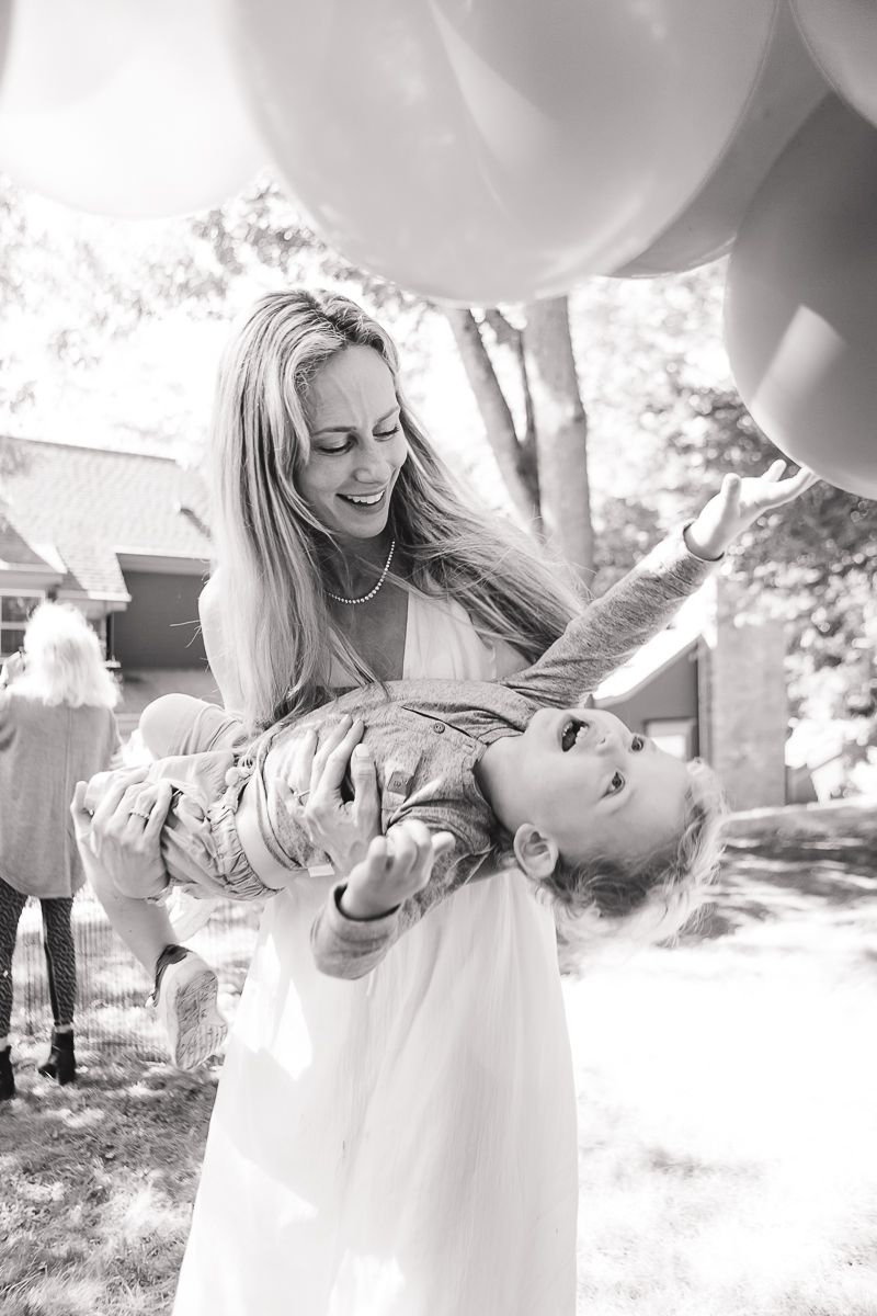 a candid black and white moment of a mother holding her toddler son and playing during a birthday party by Paula Brearley NYC family photos