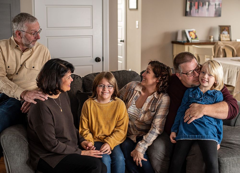 Family members share joyful moments together on a comfortable gray sofa.