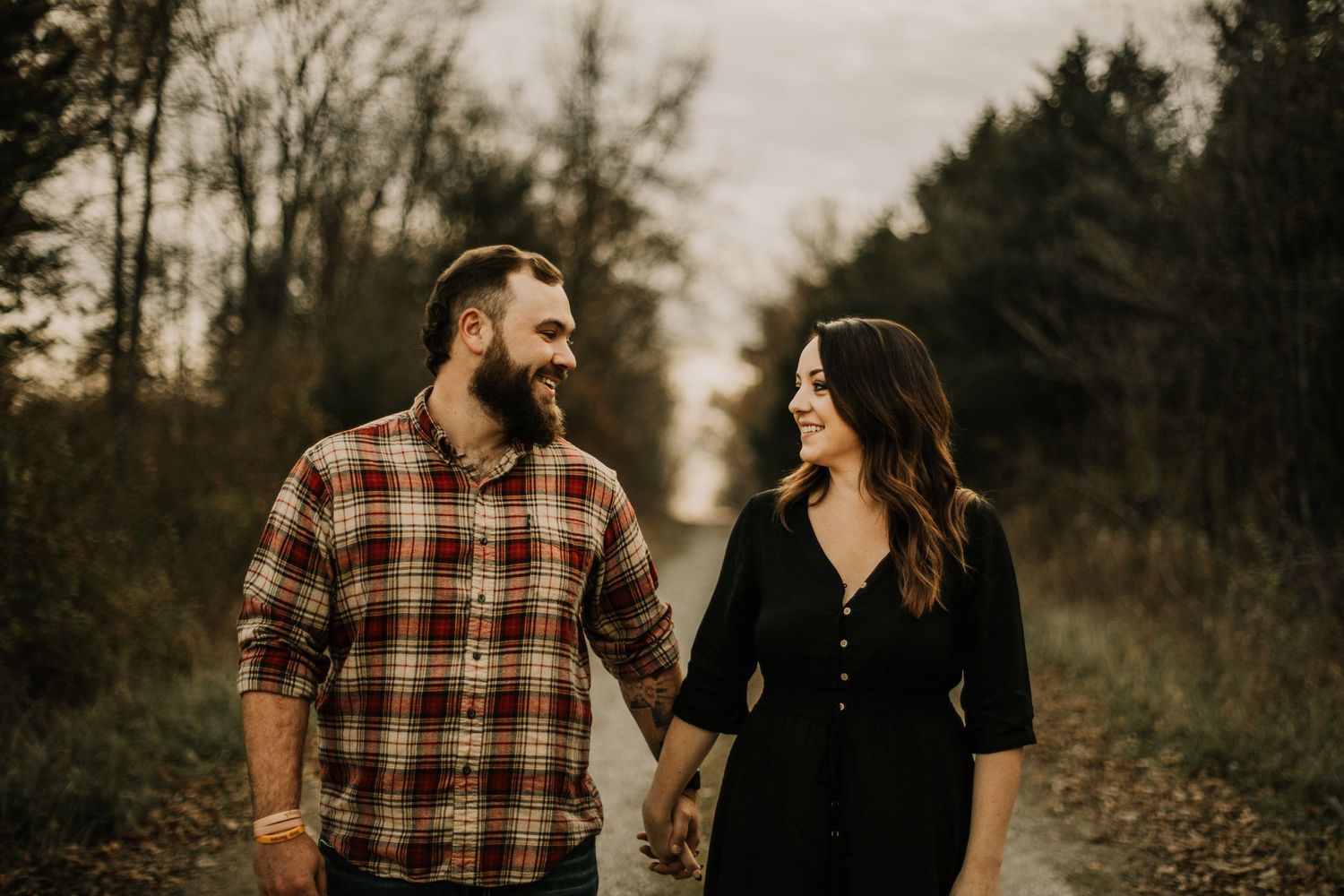 Couple laughs together during autumn photoshoot on rustic trail.