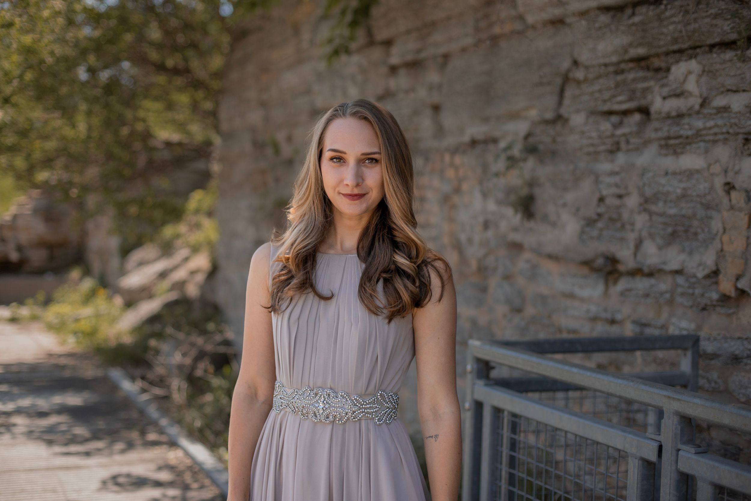 A person in an elegant gray gown stands against a rocky cliff backdrop.