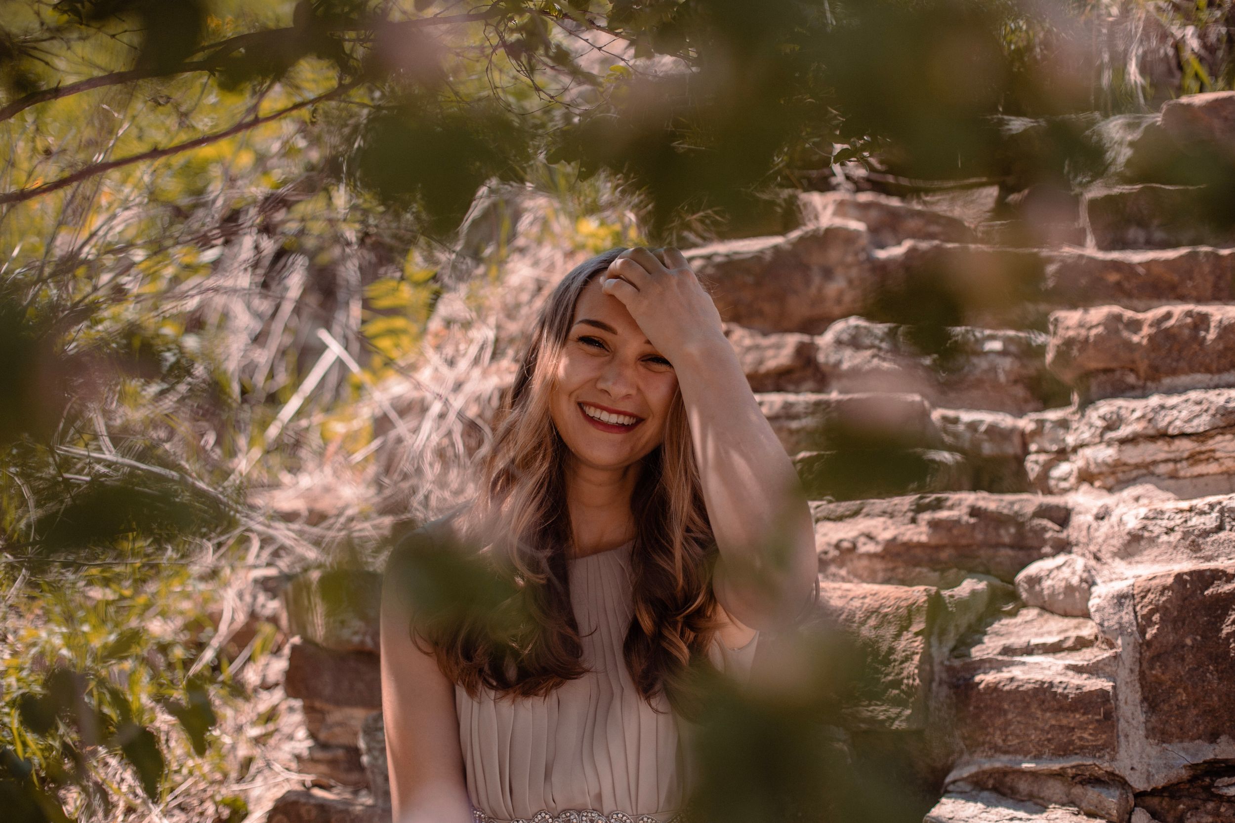 Nature portrait with soft sunlight filtering through leaves and stone wall background in warm tones.