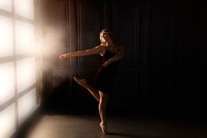 Graceful dance poses captured in dramatic lighting through window.