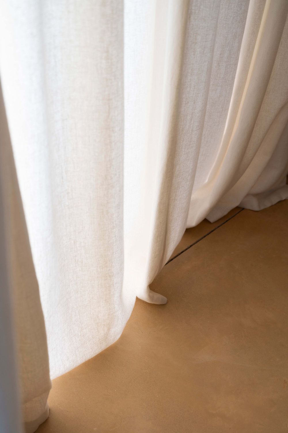 White flowing curtains draped elegantly against a light-colored wall.