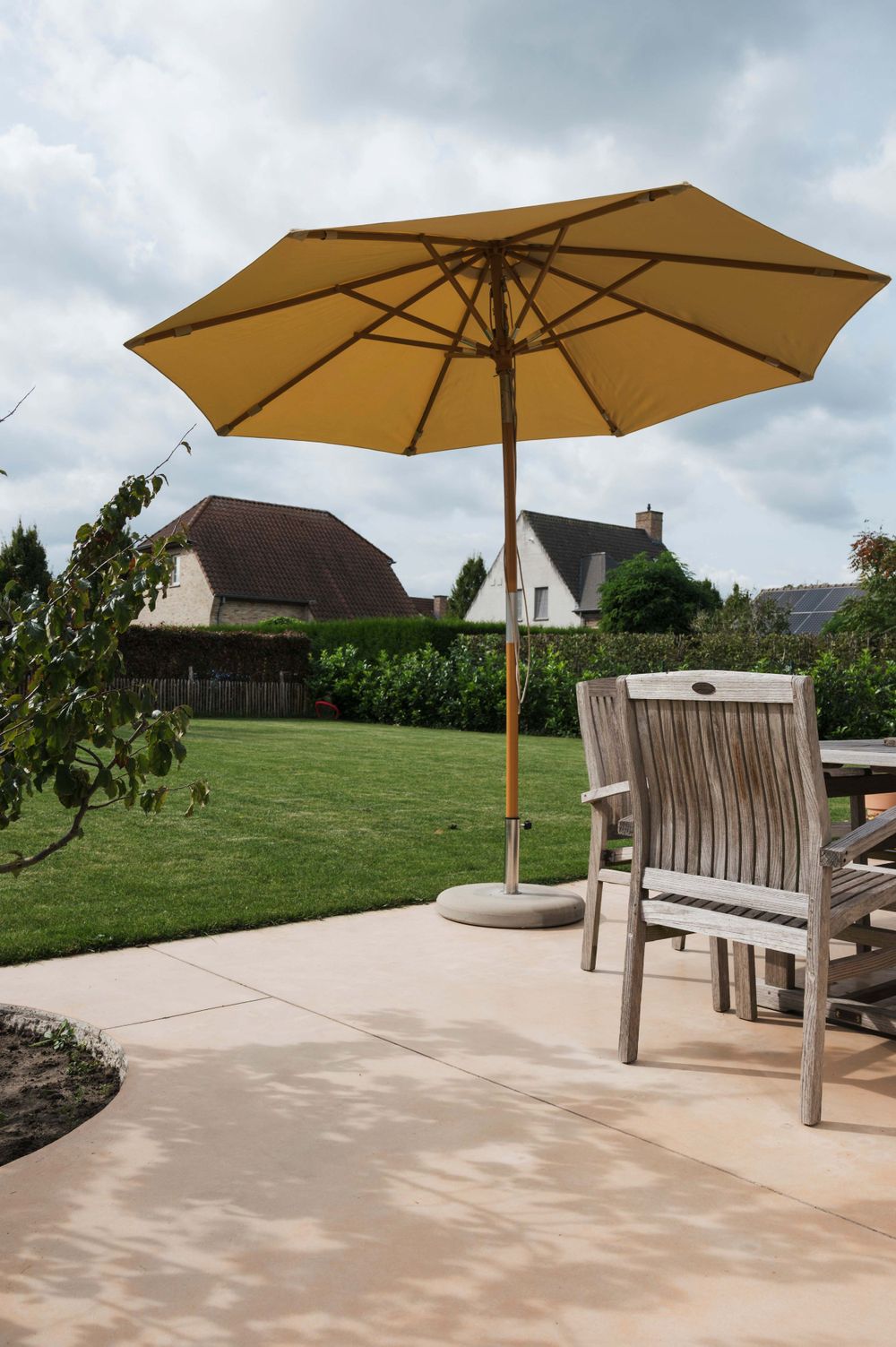 Outdoor patio area with tan umbrellas and wooden benches on concrete surface.