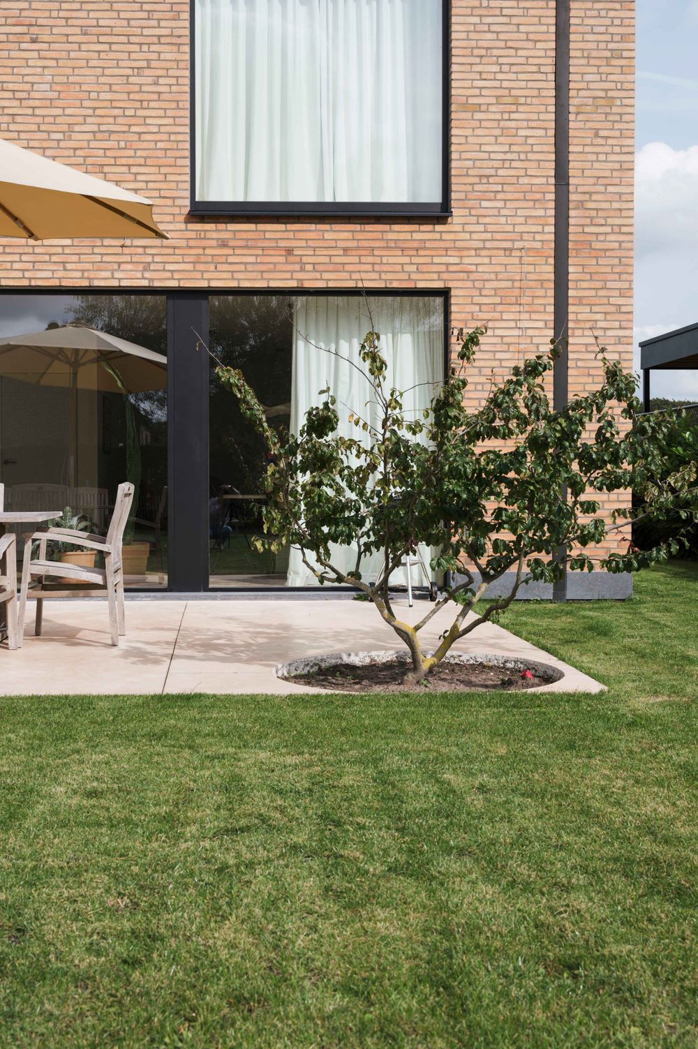 Modern brick exterior with landscaped garden and large glass windows.