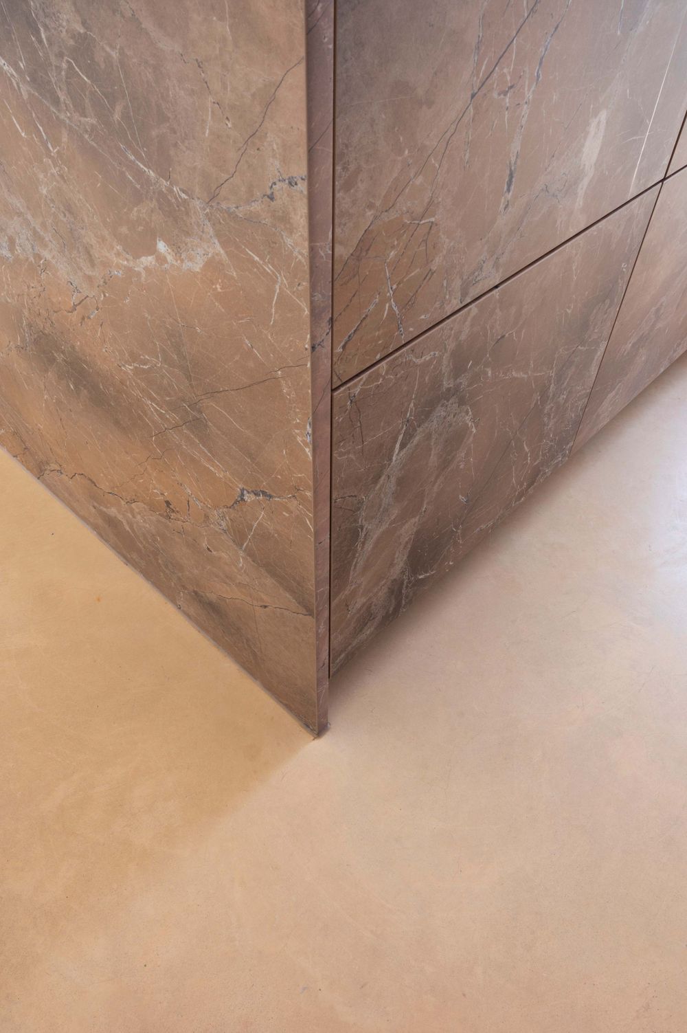 Close-up view of a textured brown marble or stone wall corner detail.