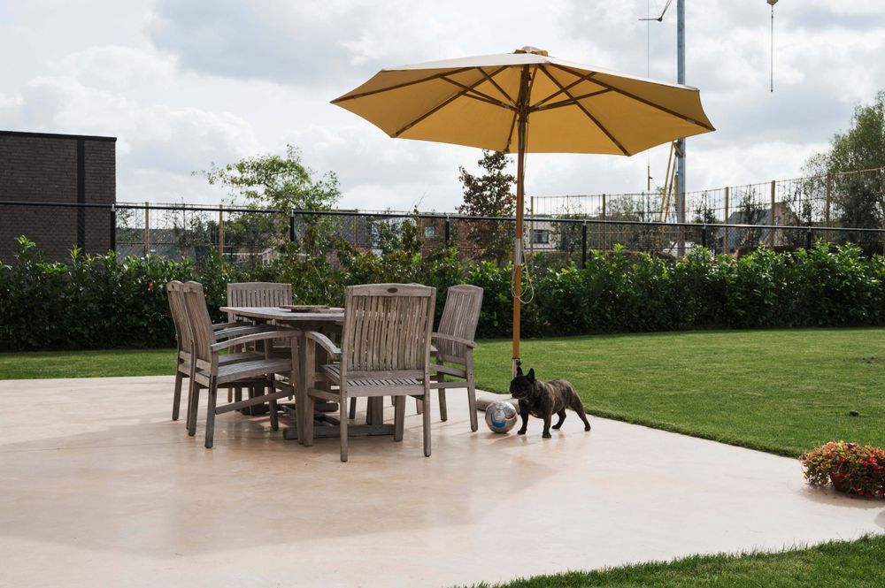 Outdoor terrace with wooden furniture and yellow umbrella overlooking a green landscape.