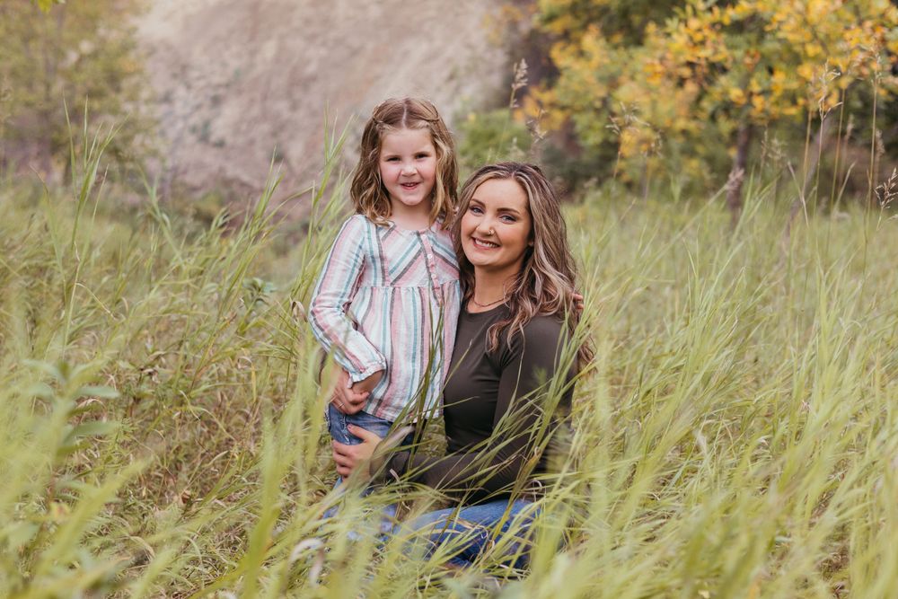 A heartwarming outdoor portrait showing two people sitting together in tall grass during golden hour.