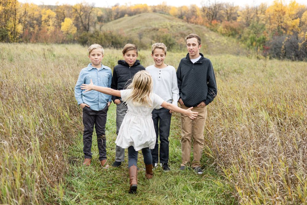 A family plays together in a golden prairie field during sunset.