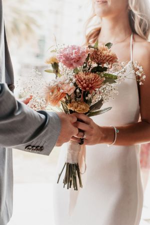 Close-up details of a delicate pink and white wedding bouquet being held.