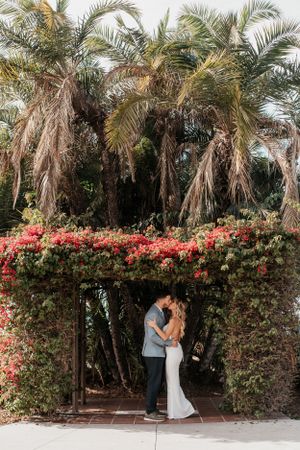 Tropical garden wedding setting with palm trees and vibrant bougainvillea arch.