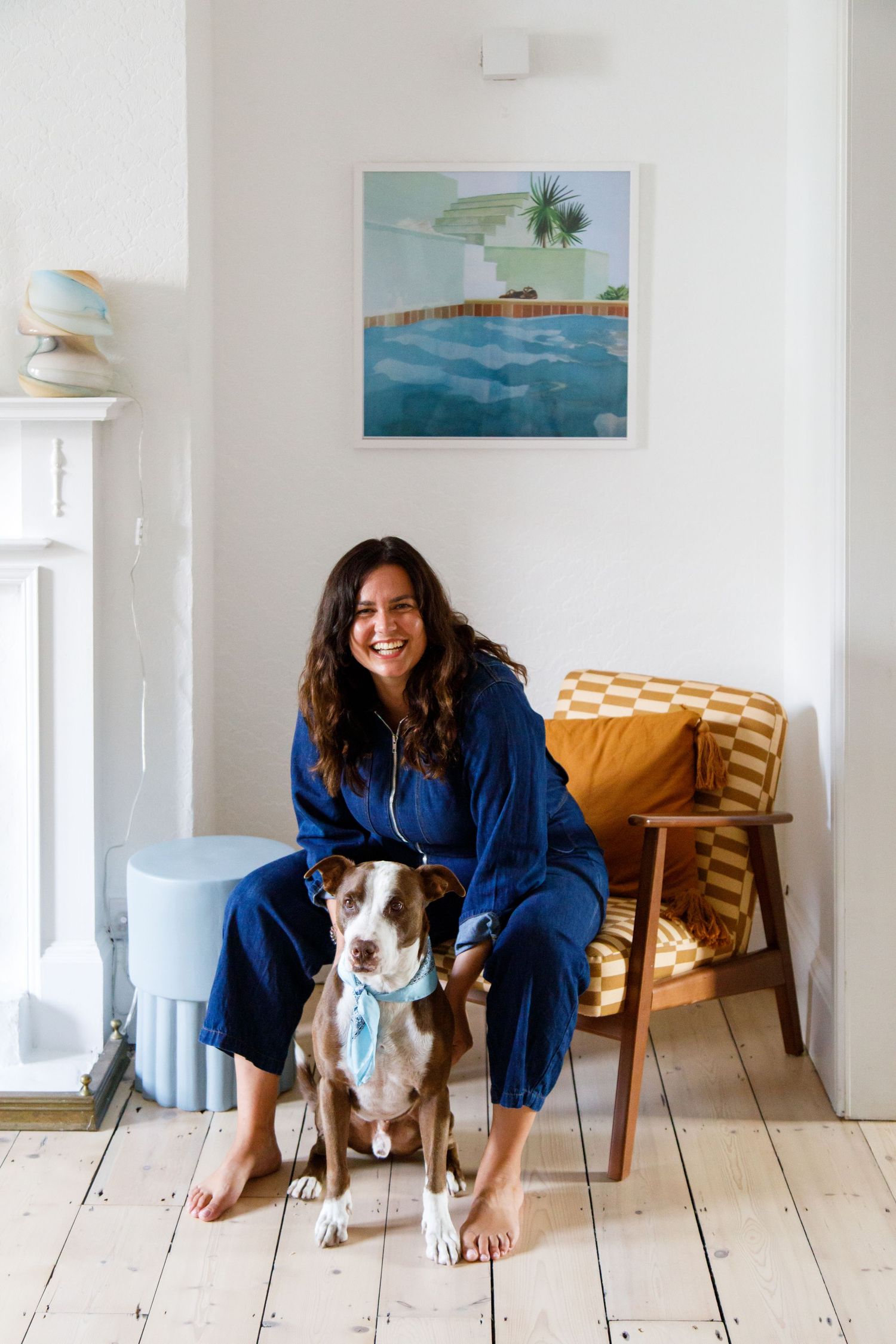 Brown and white dog sitting with owner beneath coastal artwork in bright room from a business branding photoshoot