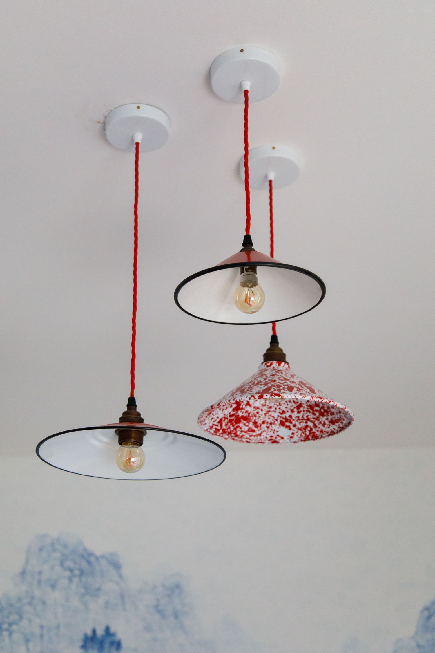 Vintage-style pendant lights with red and white glass shades hanging from white ceiling taken during an interiors/lifestyle photoshoot.