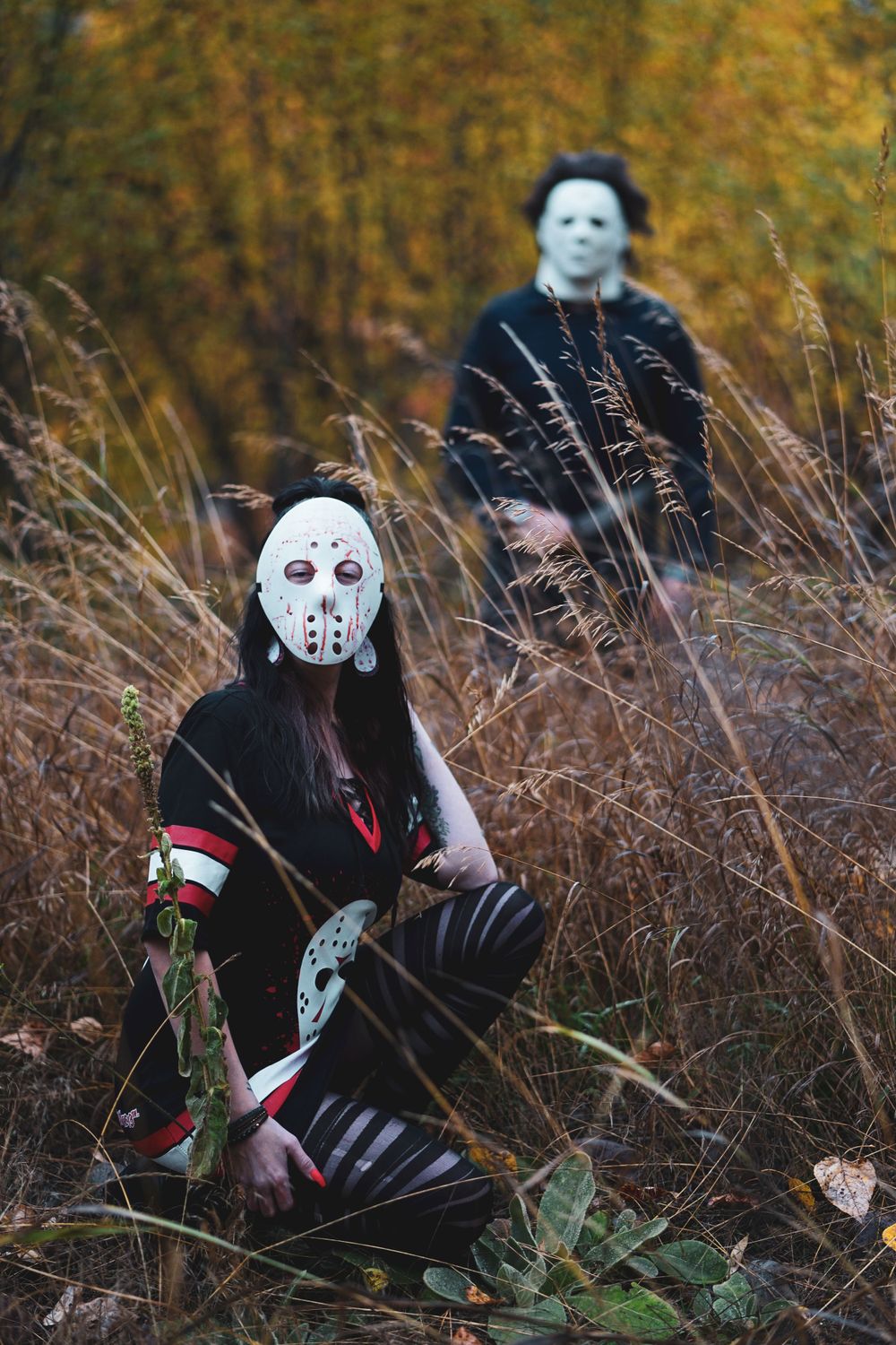 Spooky Halloween themed photo of masked figures in tall autumn grass.