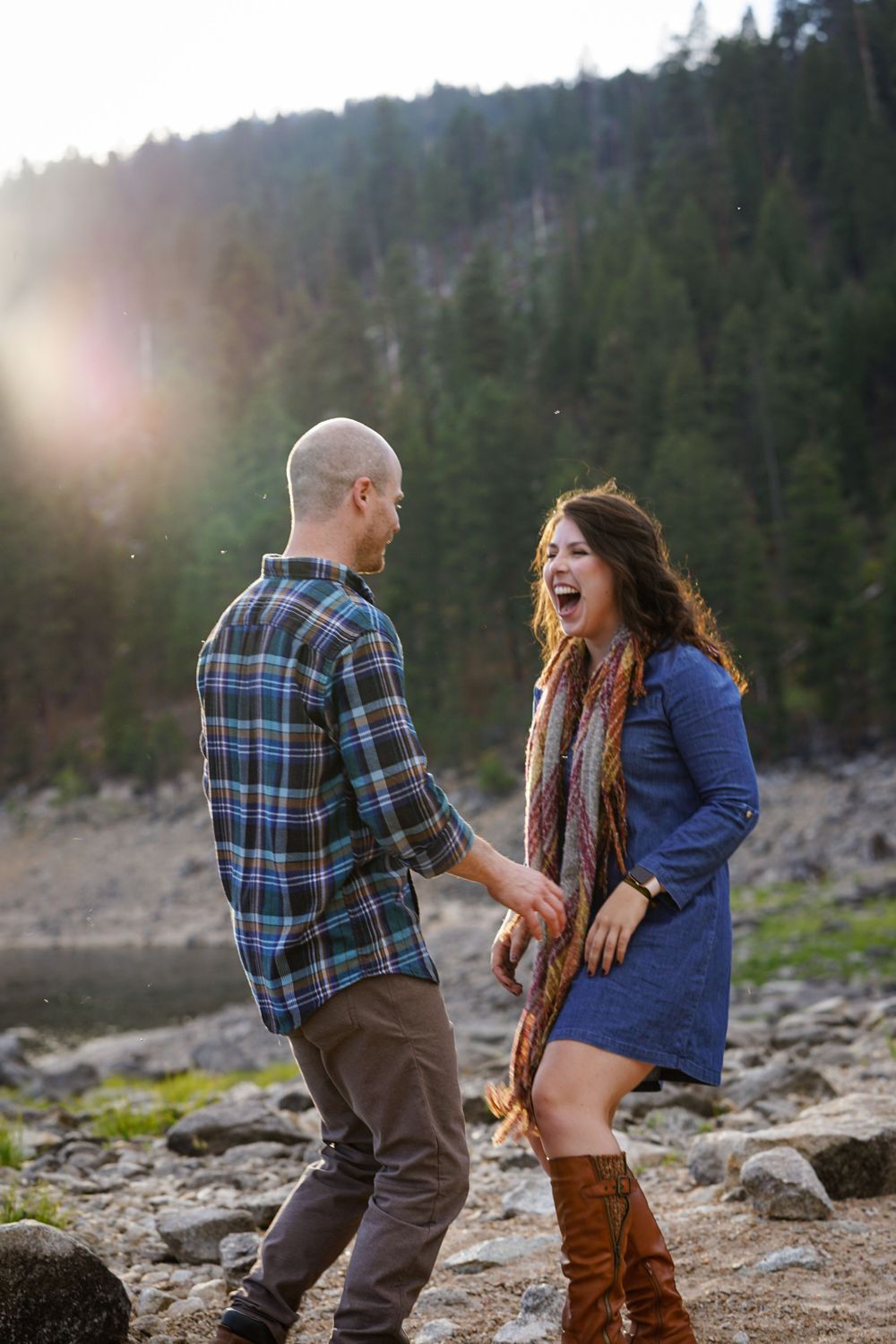 Joyful interaction between couple on rocky mountain lakeside.