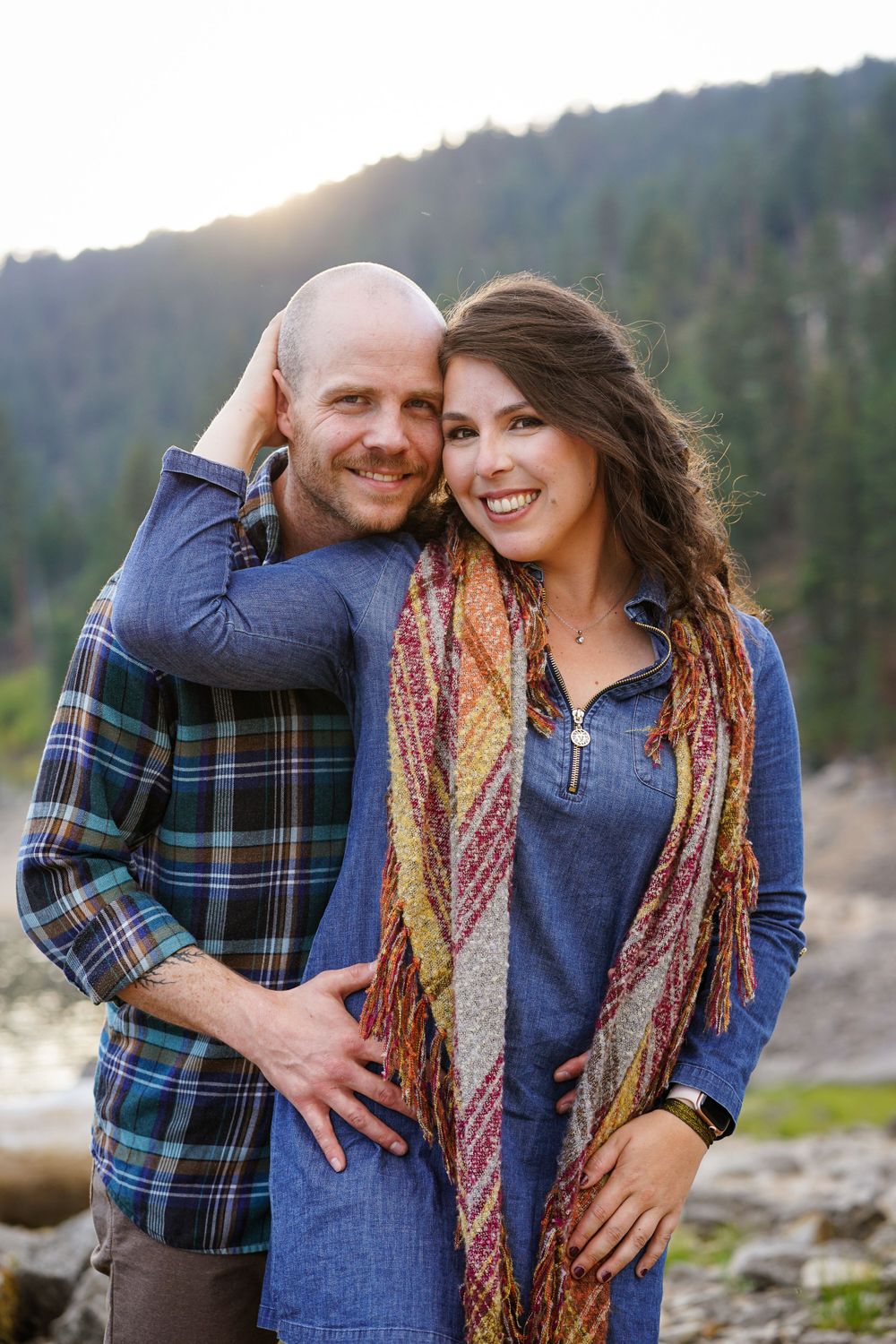 Couple poses together on mountain shore during golden hour.