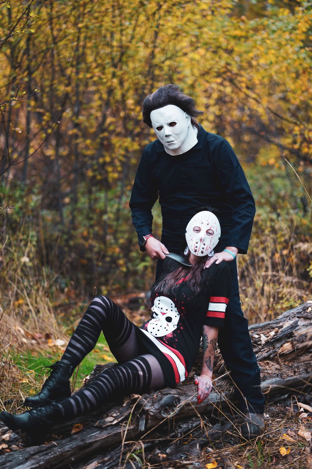Horror-themed photoshoot featuring people in masks posing dramatically against autumn foliage.