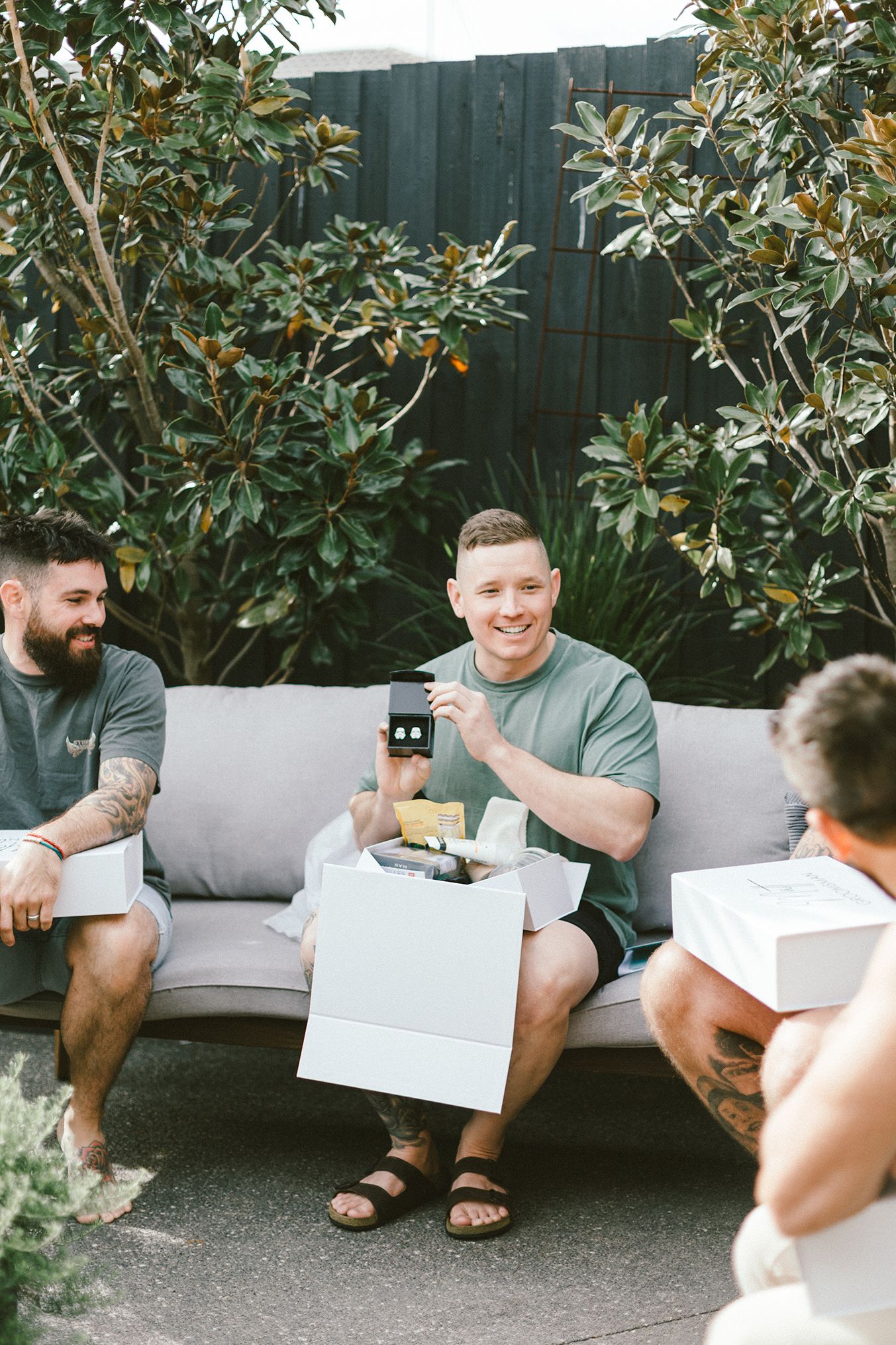 Friends sharing reactions while reading documents on outdoor patio sofa.