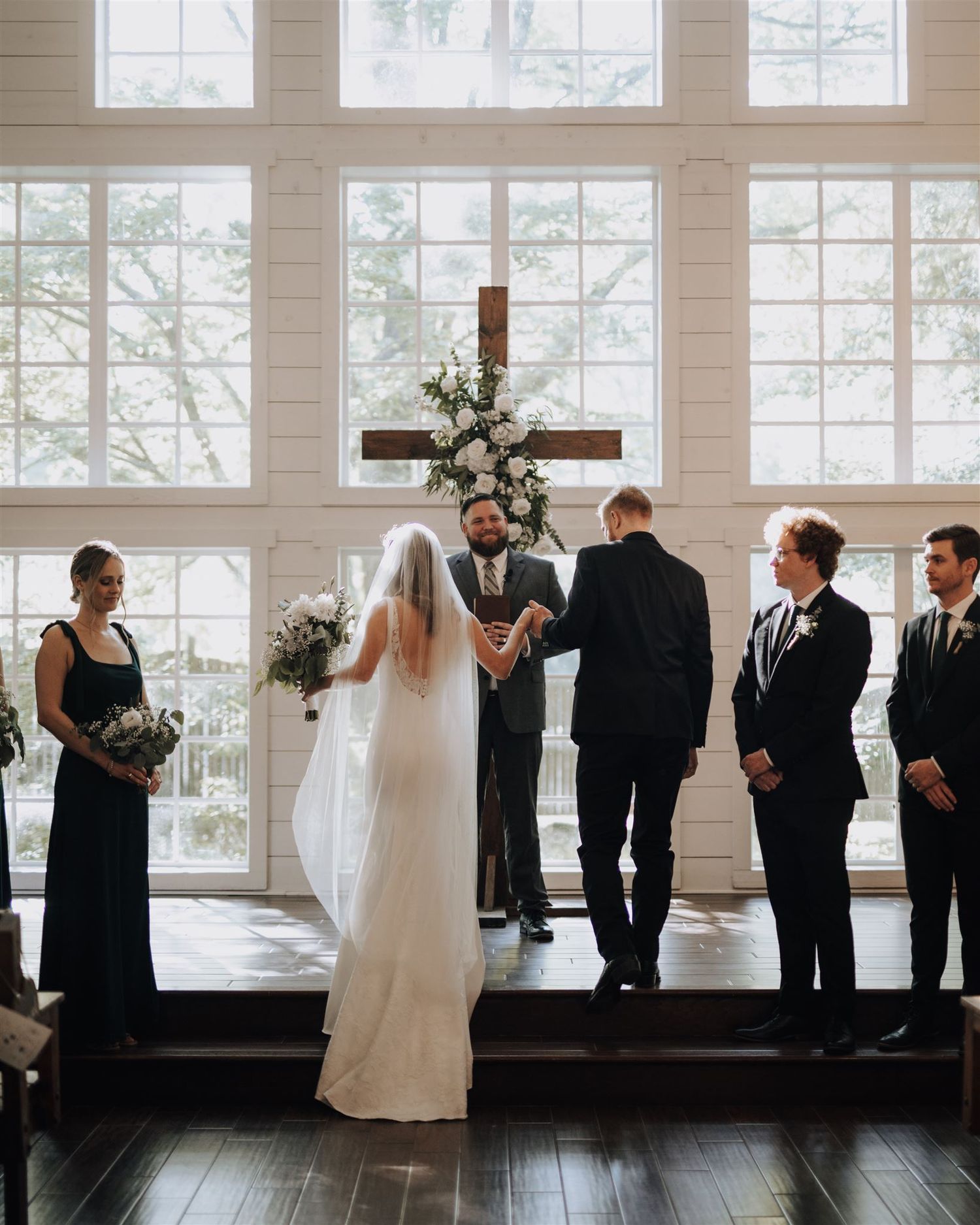 A wedding ceremony in progress at an elegant white chapel with natural lighting.