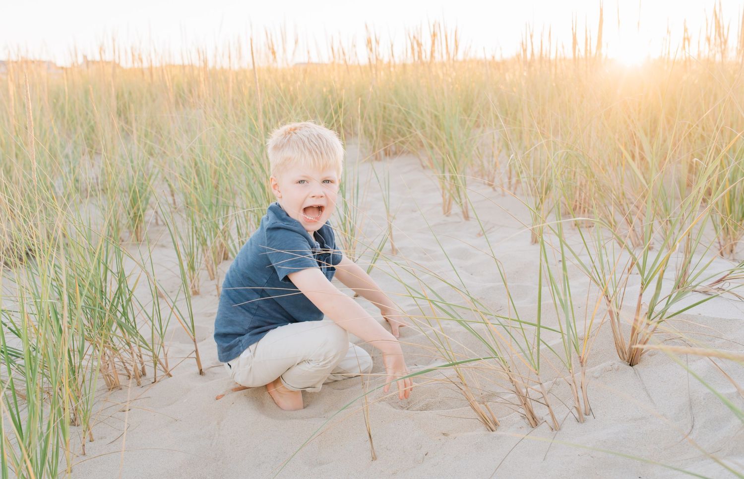 A young blond haired boy playing in the sand.