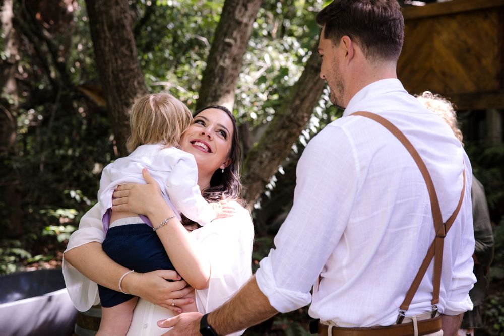 A tender family embrace in a sun-dappled forest setting.