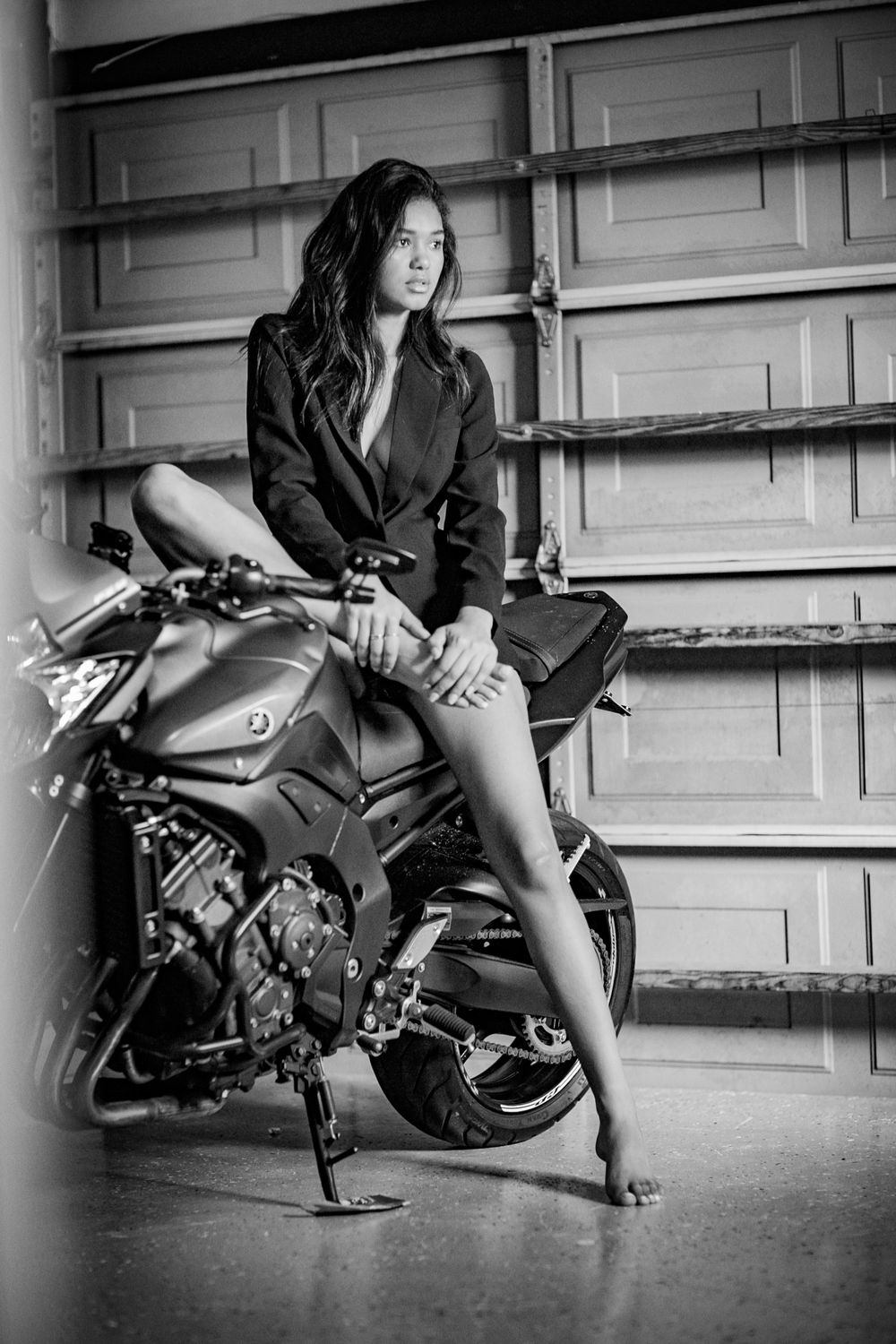 Black and white photo series featuring poses with a motorcycle in an industrial setting.