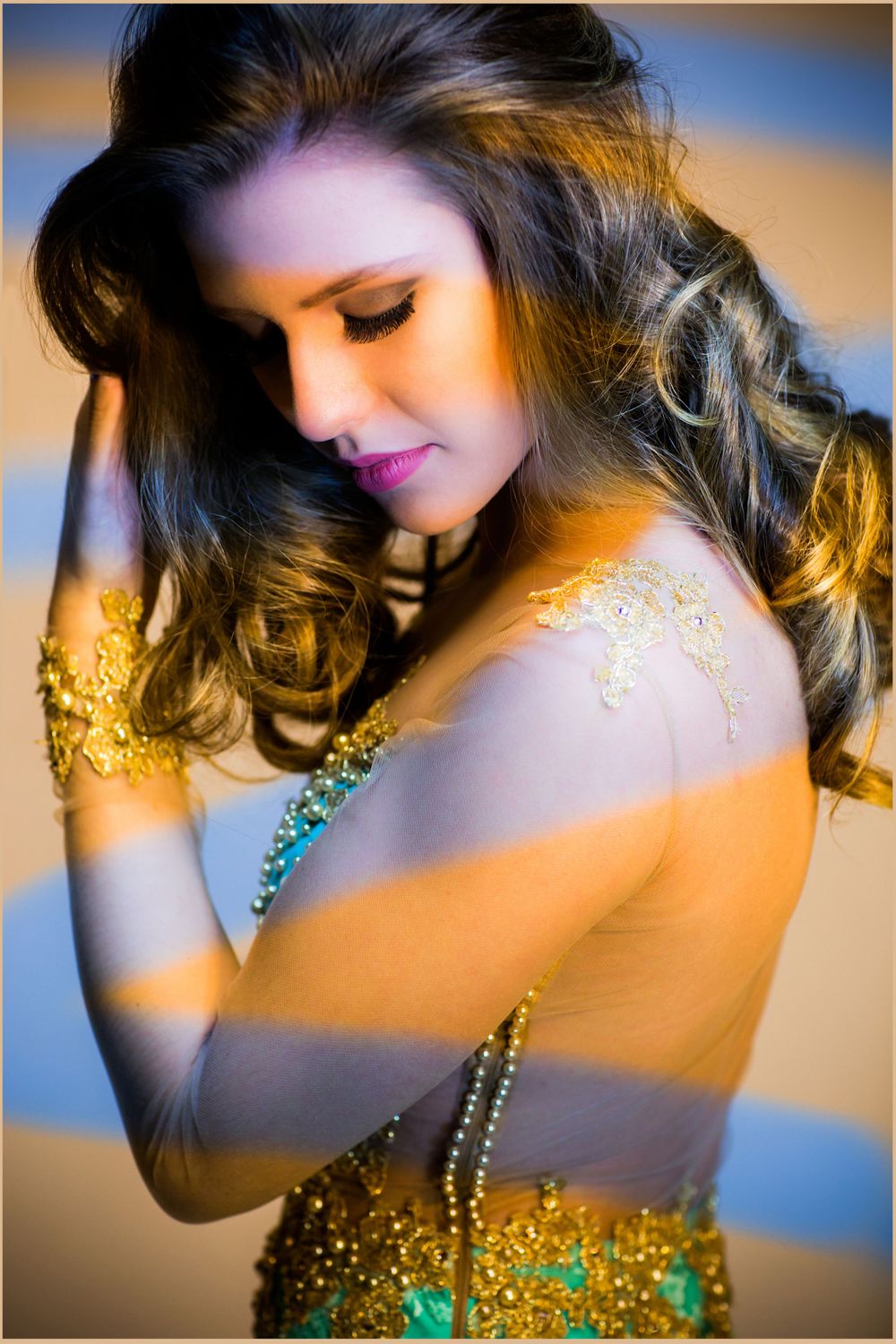 Close-up beauty portrait with golden glitter makeup and dramatic side lighting.