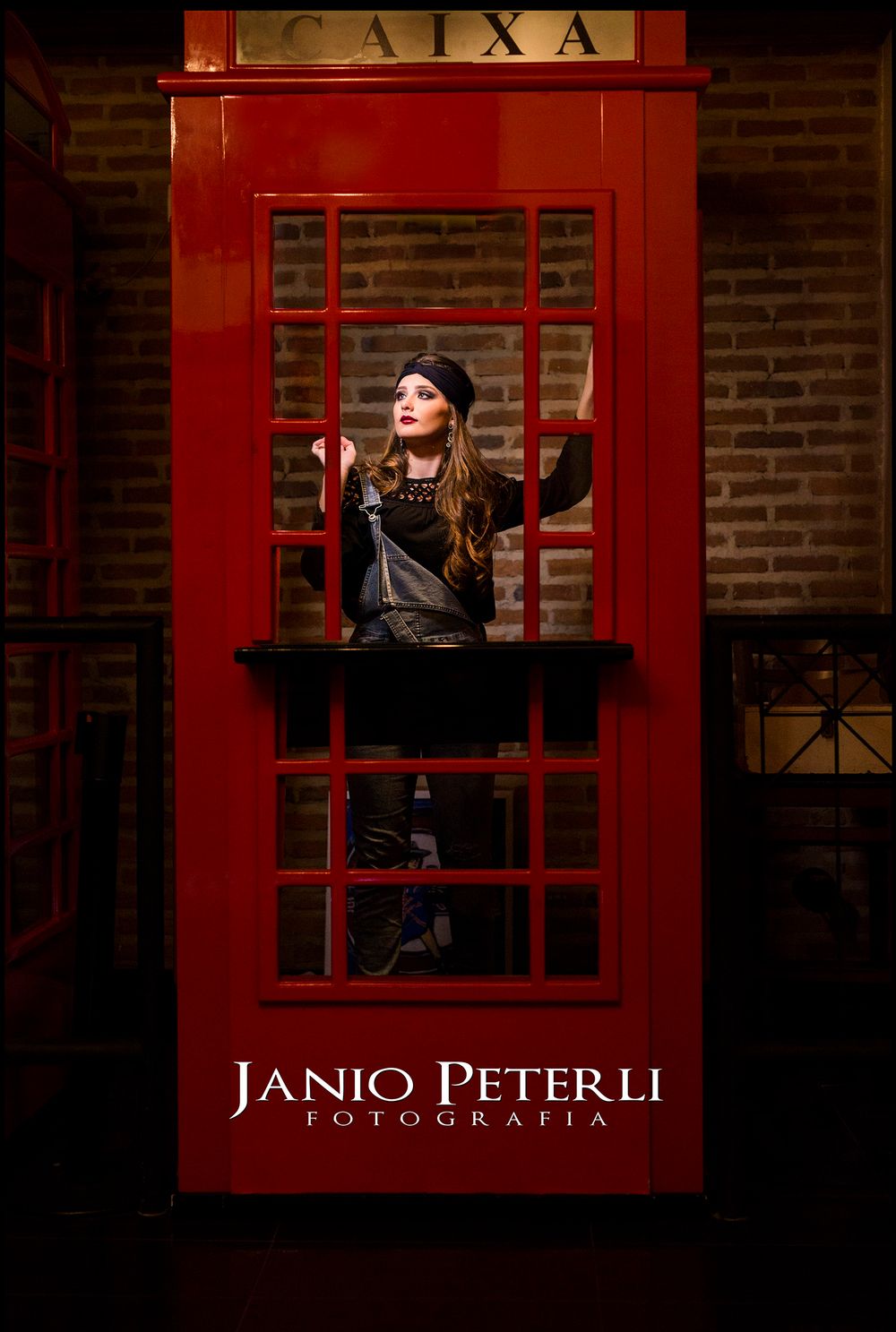 Model poses in vintage red telephone booth with artistic lighting.