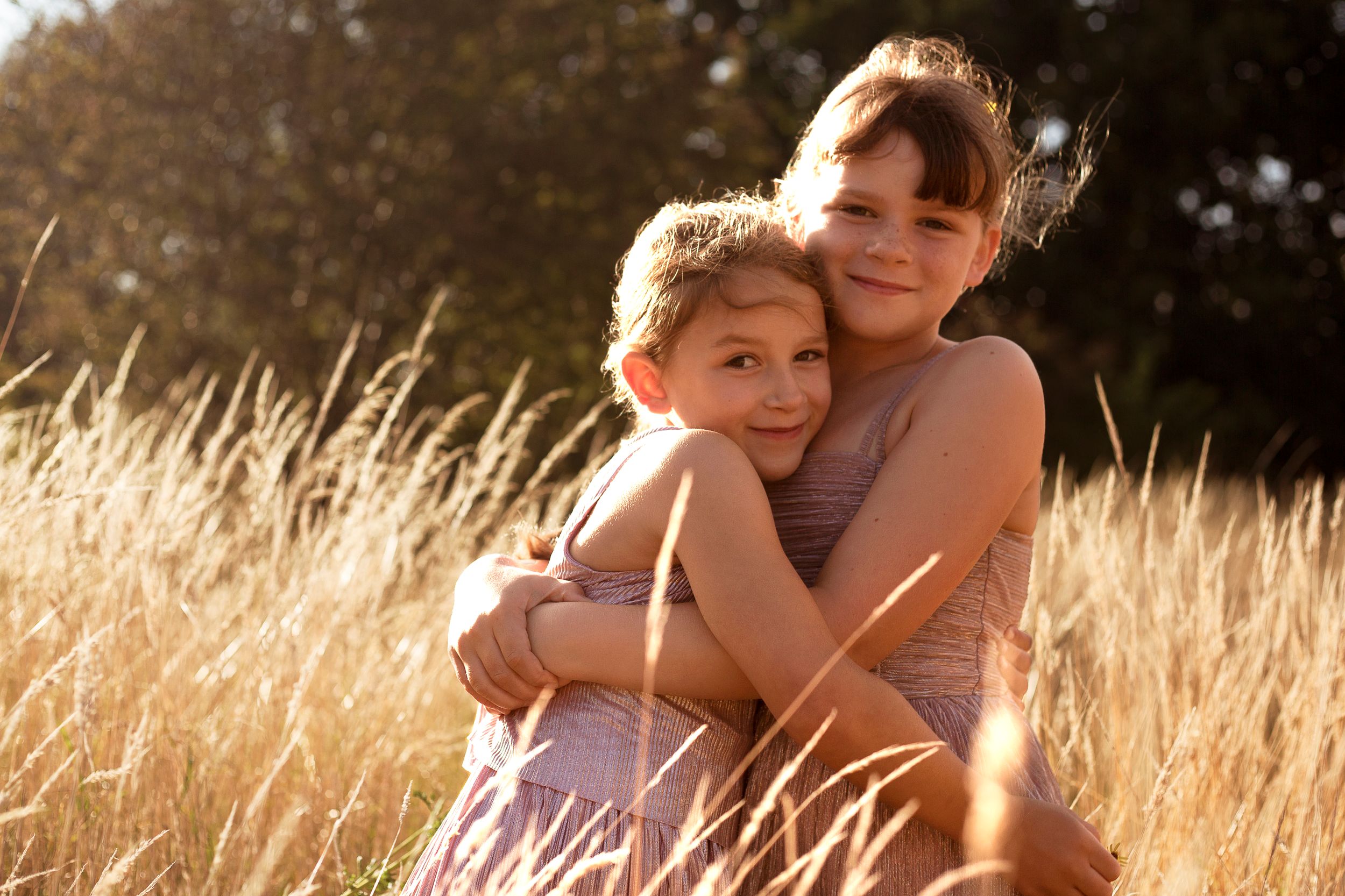 Sisters embracing in golden meadow in dorset