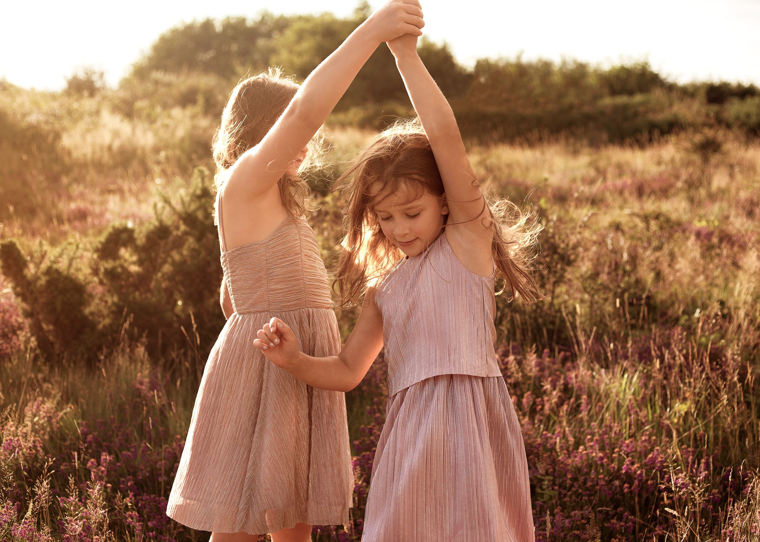 Sisters dancing in summer meadow in dorset