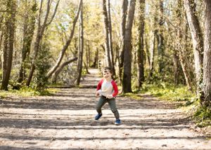 Playful photoshoot of young boy running in the woods