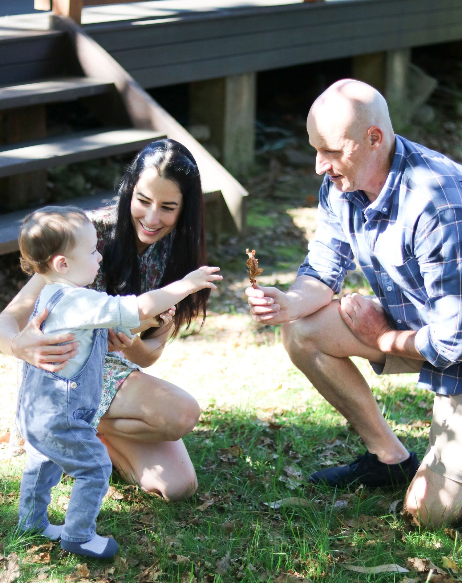 Playful outdoor scene with people crouching in grass on a sunny day.