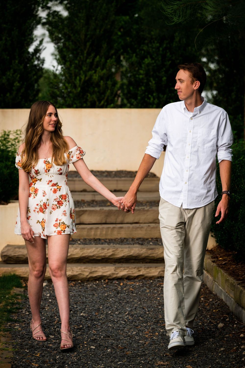 Couple holding hands while walking along outdoor steps, wearing summer outfits.