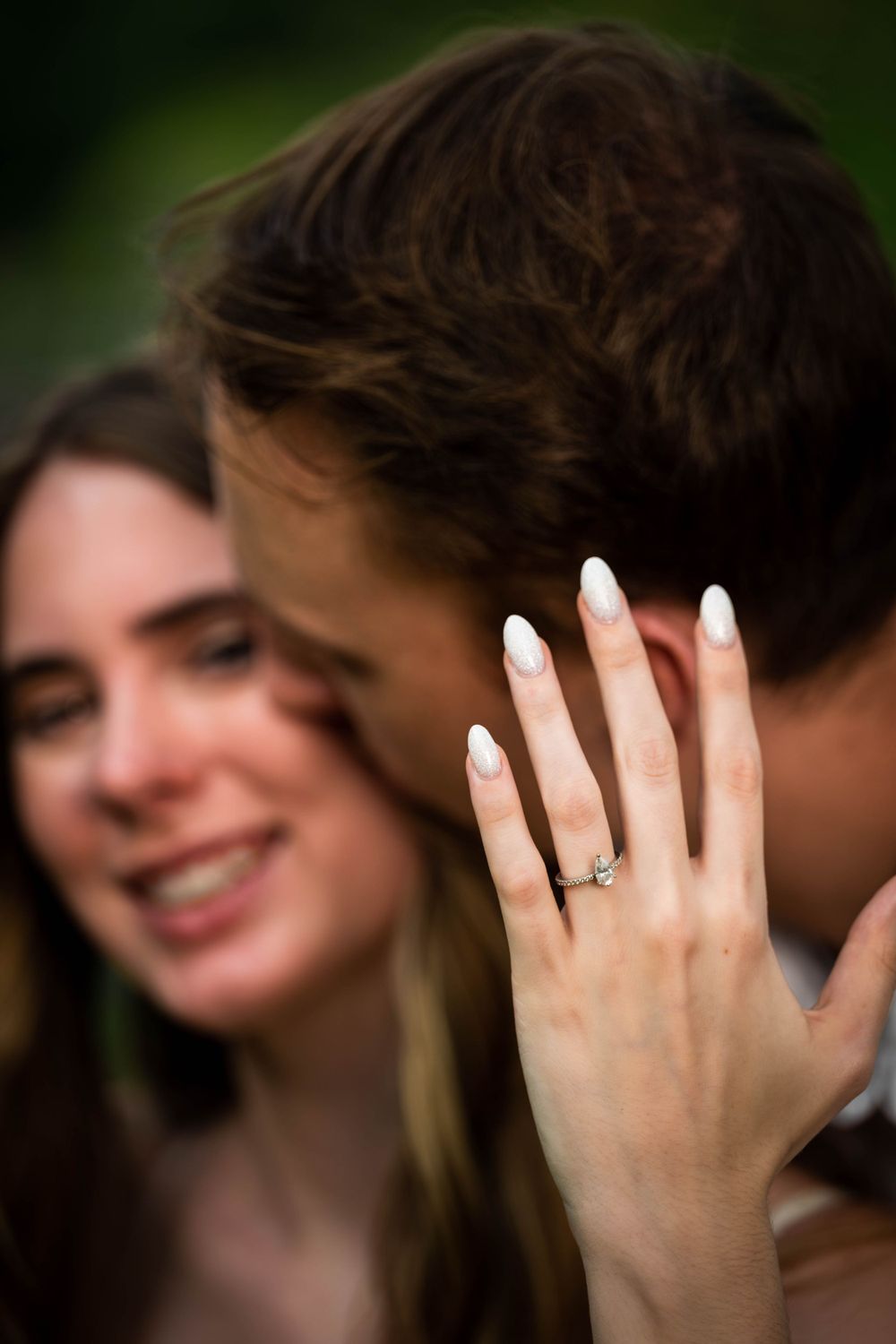 Close-up shot highlighting an engagement ring during a romantic couple's photoshoot.