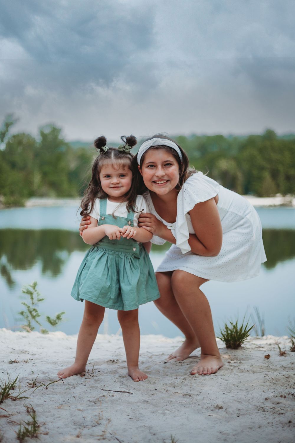 Parent and child playing together on a sandy beach near the water.