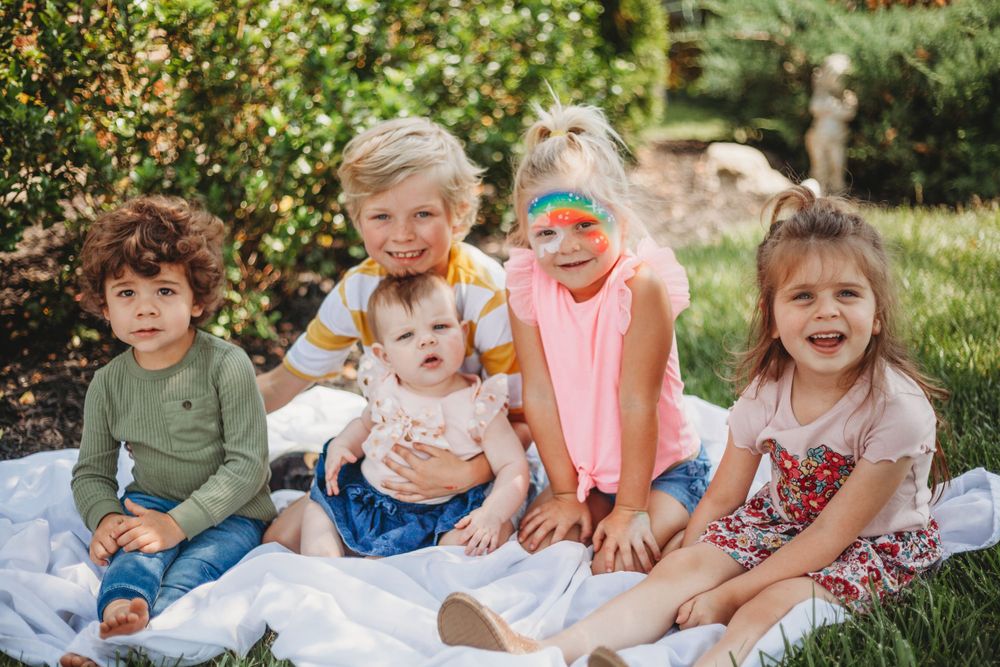 Group of children sitting together on grass during a sunny day.