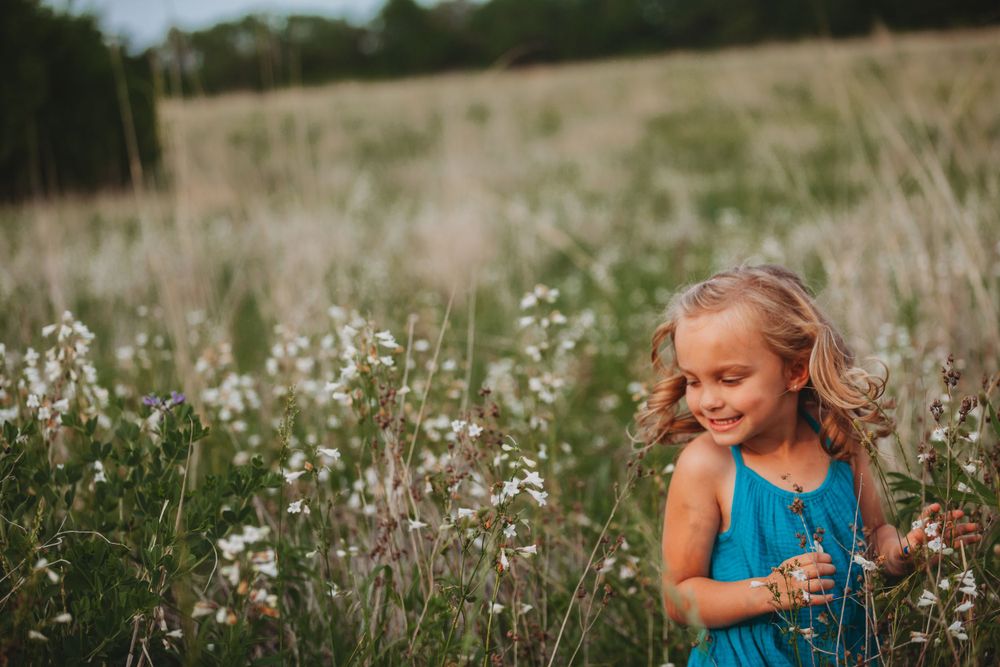 Young children playing in a wildflower meadow on a sunny summer day.