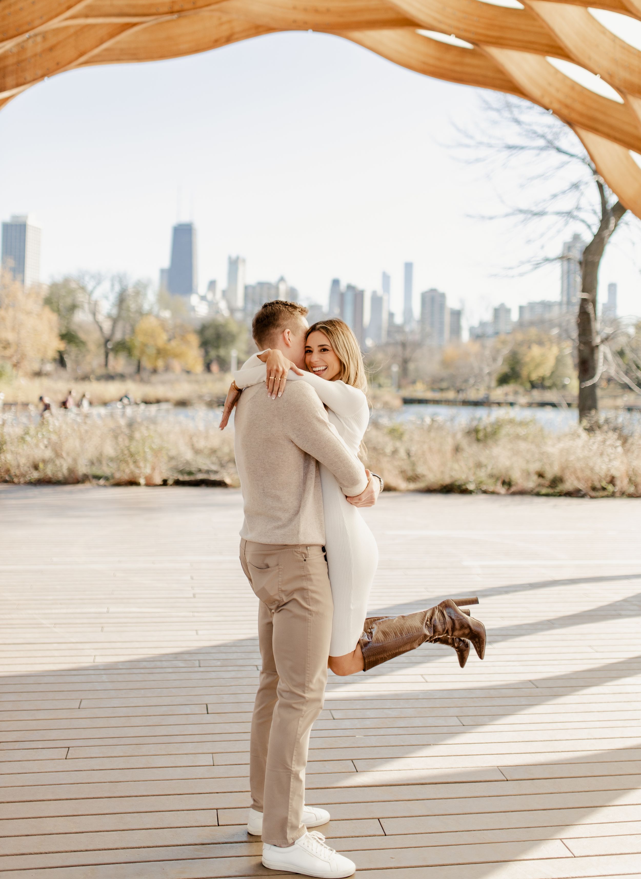 Romantic embrace with Chicago skyline in background during engagement photo session.