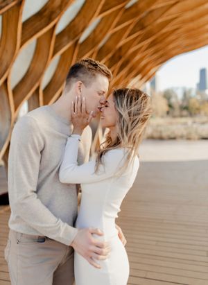 Intimate moment between couple in matching neutral outfits sharing a tender kiss under wooden beams.
