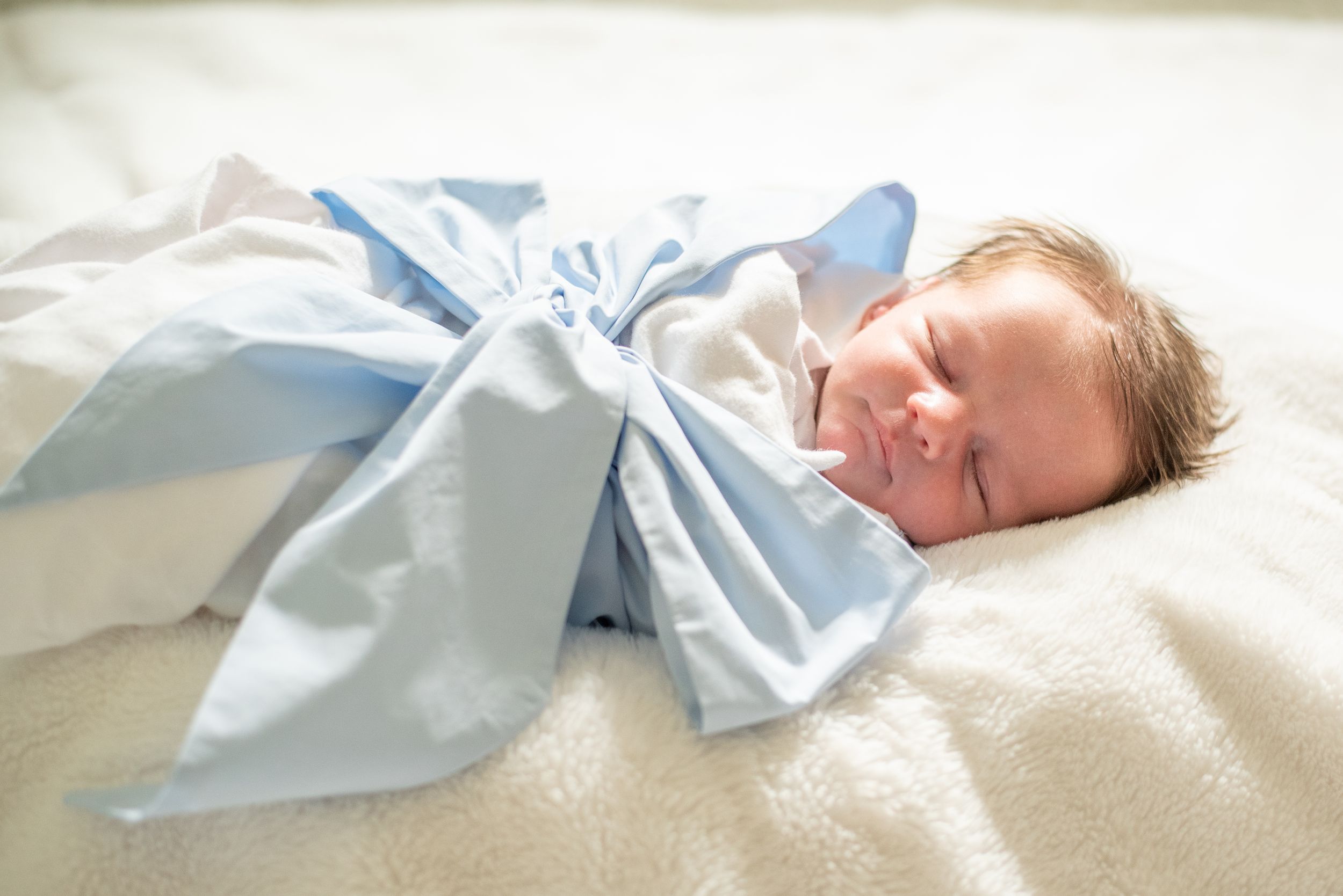 precious baby boy. Newborn baby boy wrapped in a bow during in home Houston boutique newborn photography session