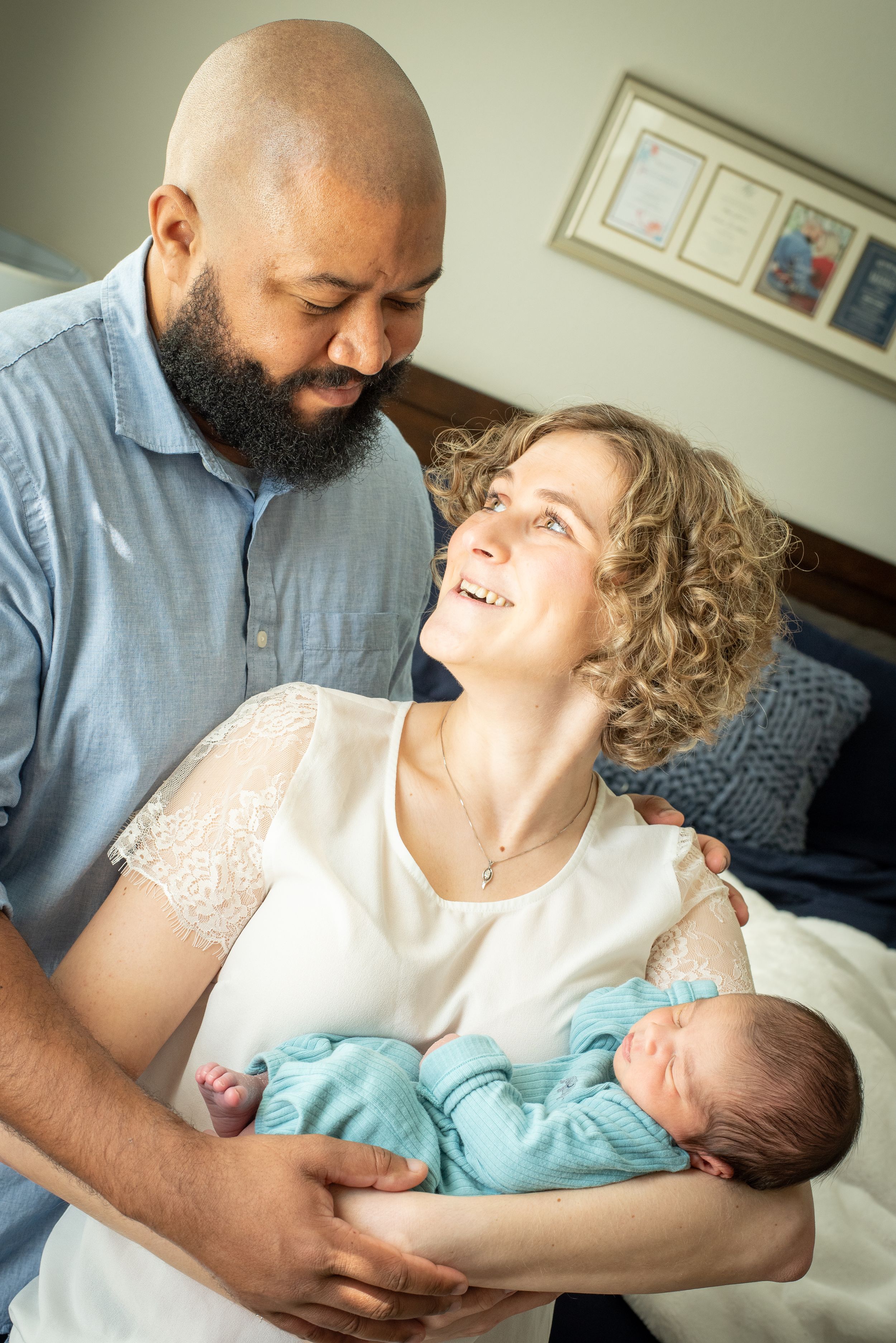 celebrating becoming a family of 3. new mom and dad with Newborn baby during Houston newborn photography session in home.