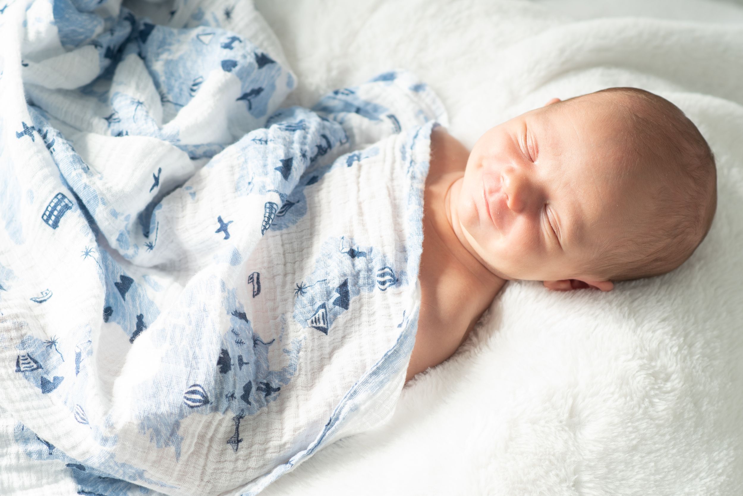 that smile melts our hearts. Newborn baby wrapped in soft blanket during Houston in home newborn photography session